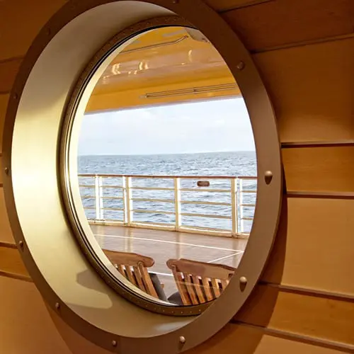 A view of the ocean from inside a porthole window.