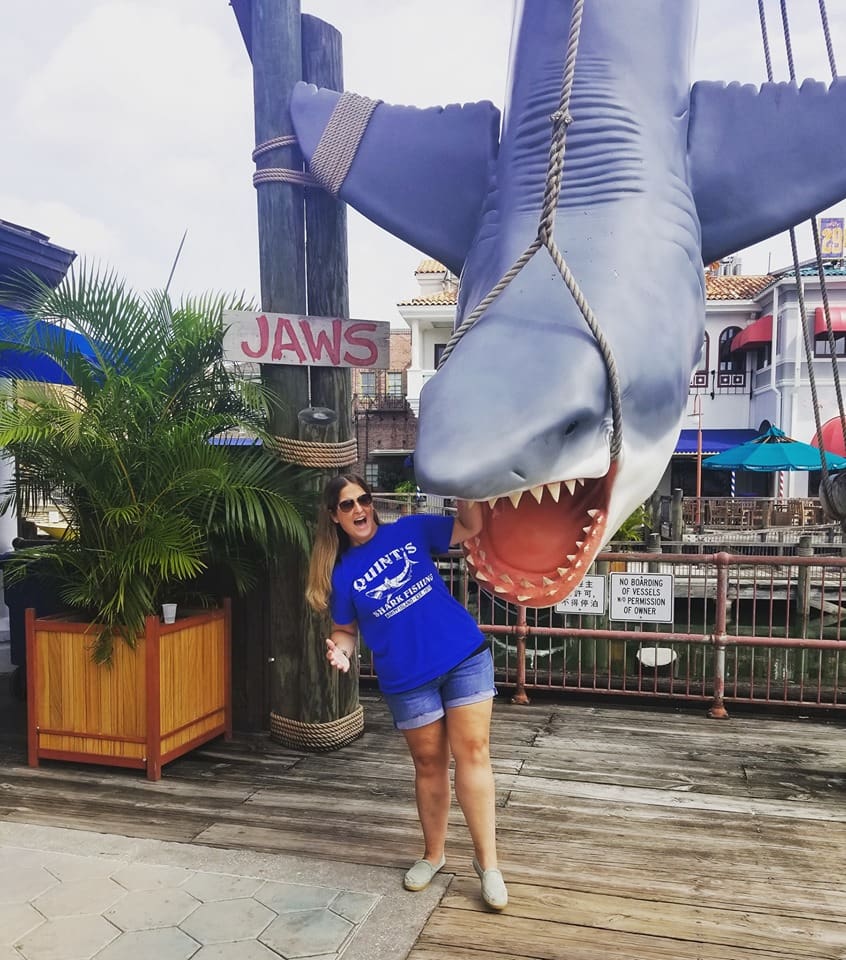 A woman standing next to a shark statue.