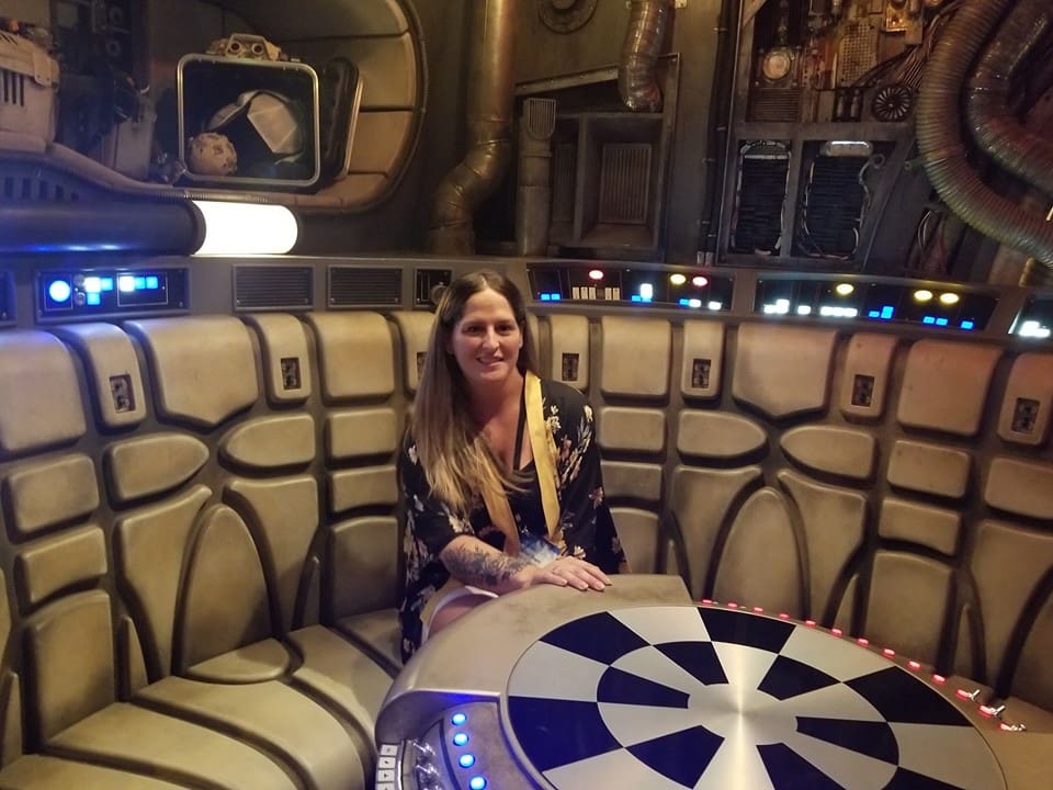 A woman sitting at the table in front of a spaceship.