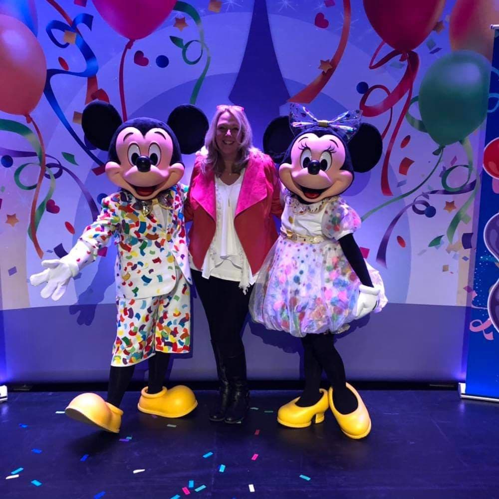 A woman standing between two mickey mouse characters.