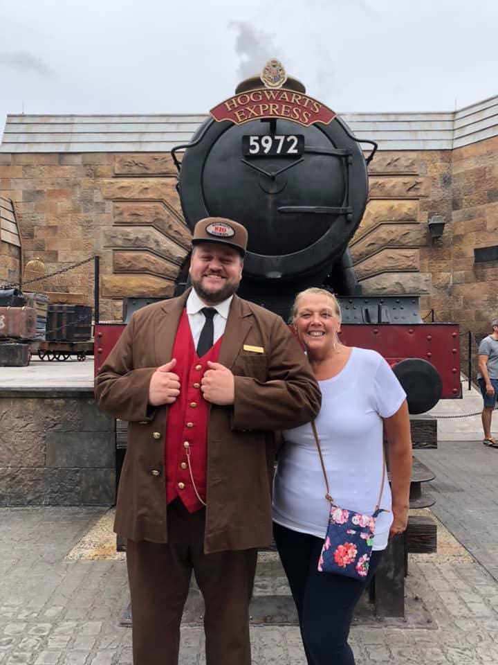 A man and woman posing in front of a train.