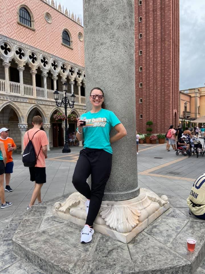 A woman leaning against a pillar in the middle of a street.