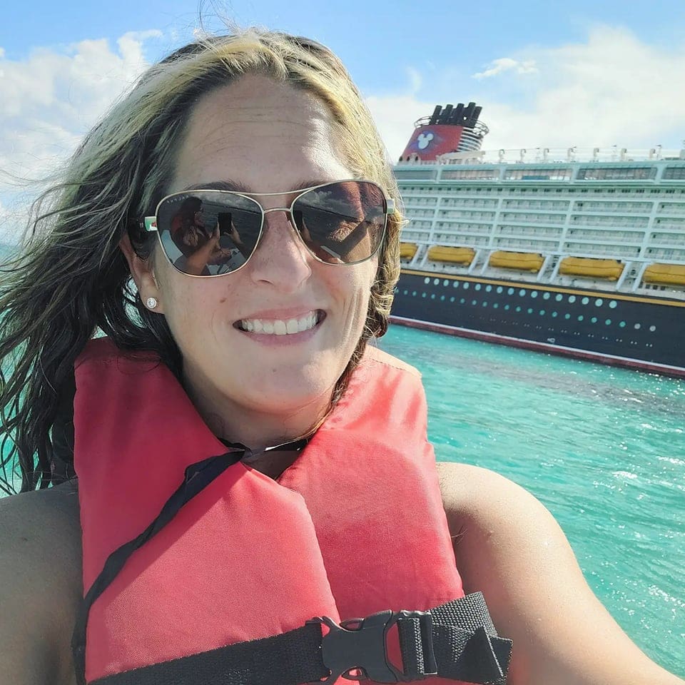 A woman in sunglasses and life jacket on the water.