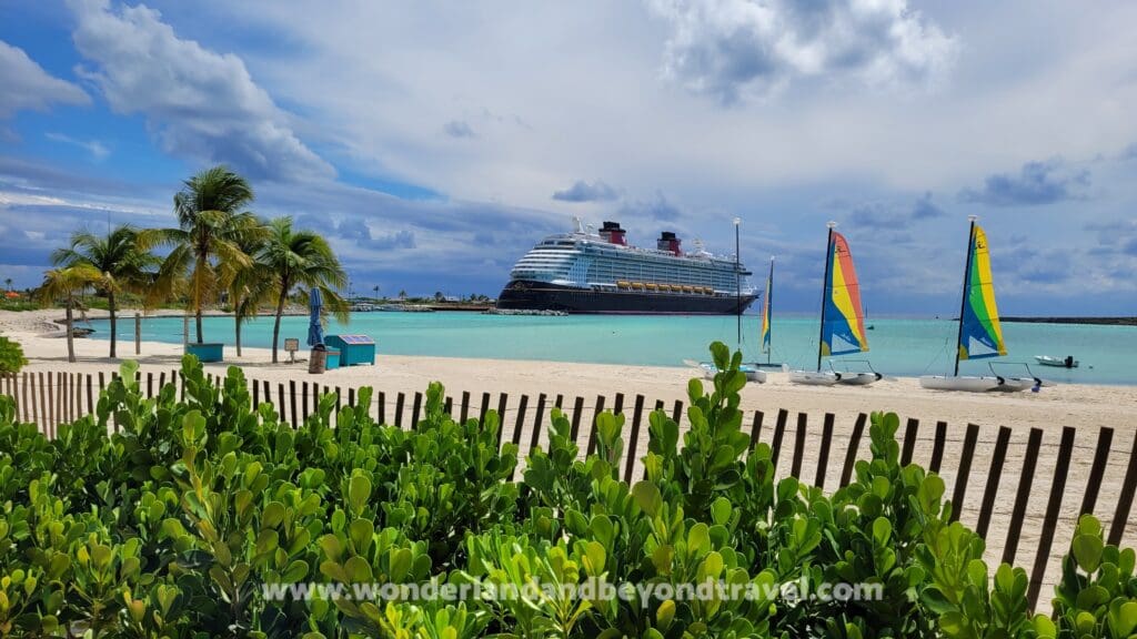 A cruise ship docked at the beach in front of a resort.