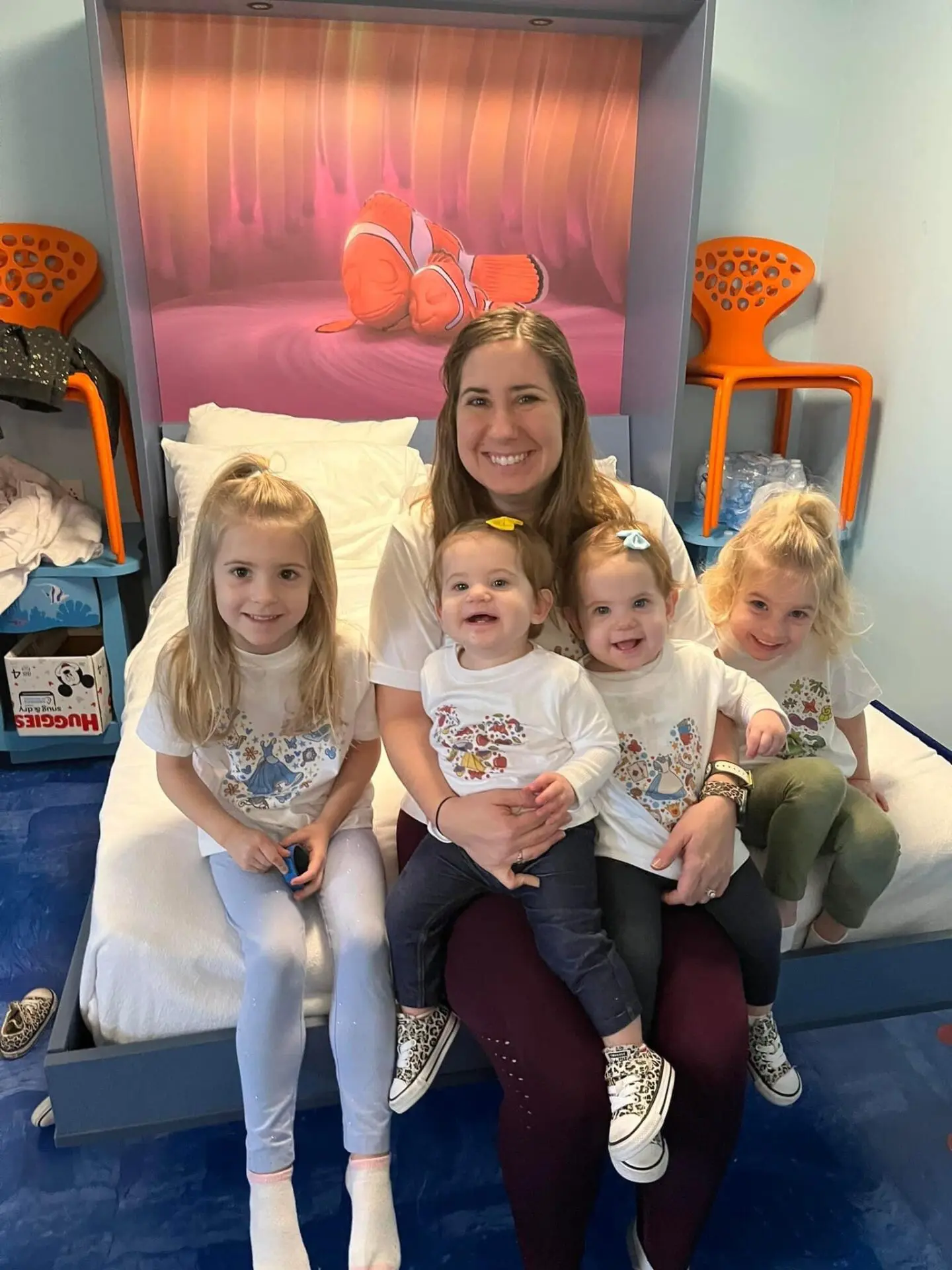 A woman sitting on top of a bed with four kids.