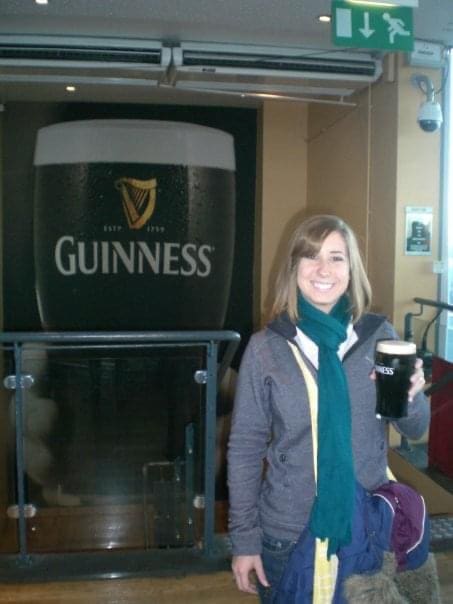 A woman standing in front of a guinness sign.