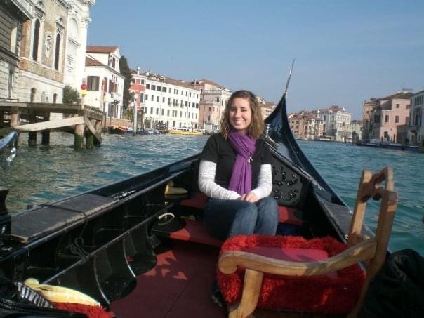 A woman sitting on the back of a boat in water.