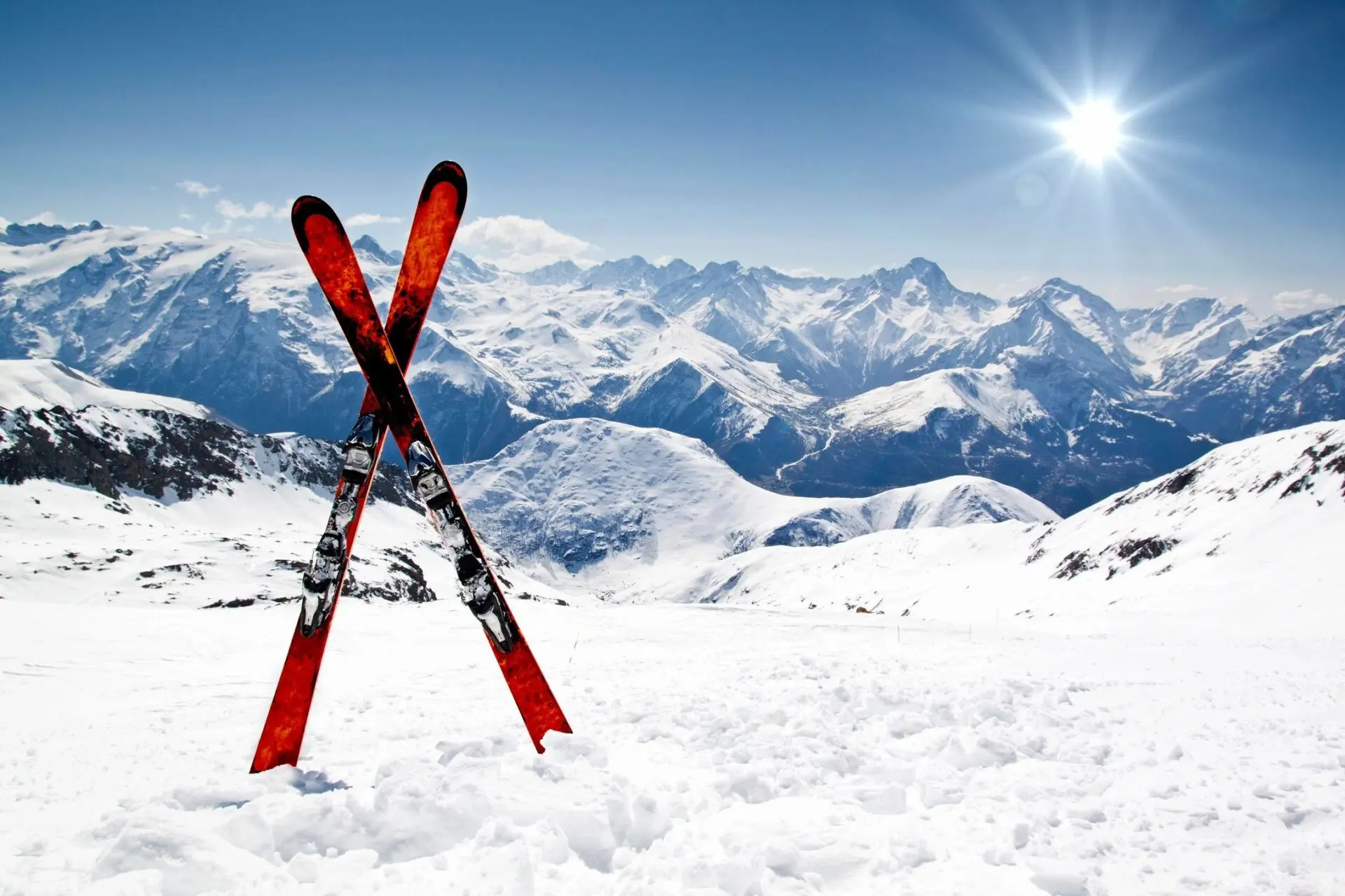 A pair of skis in the snow with mountains behind.