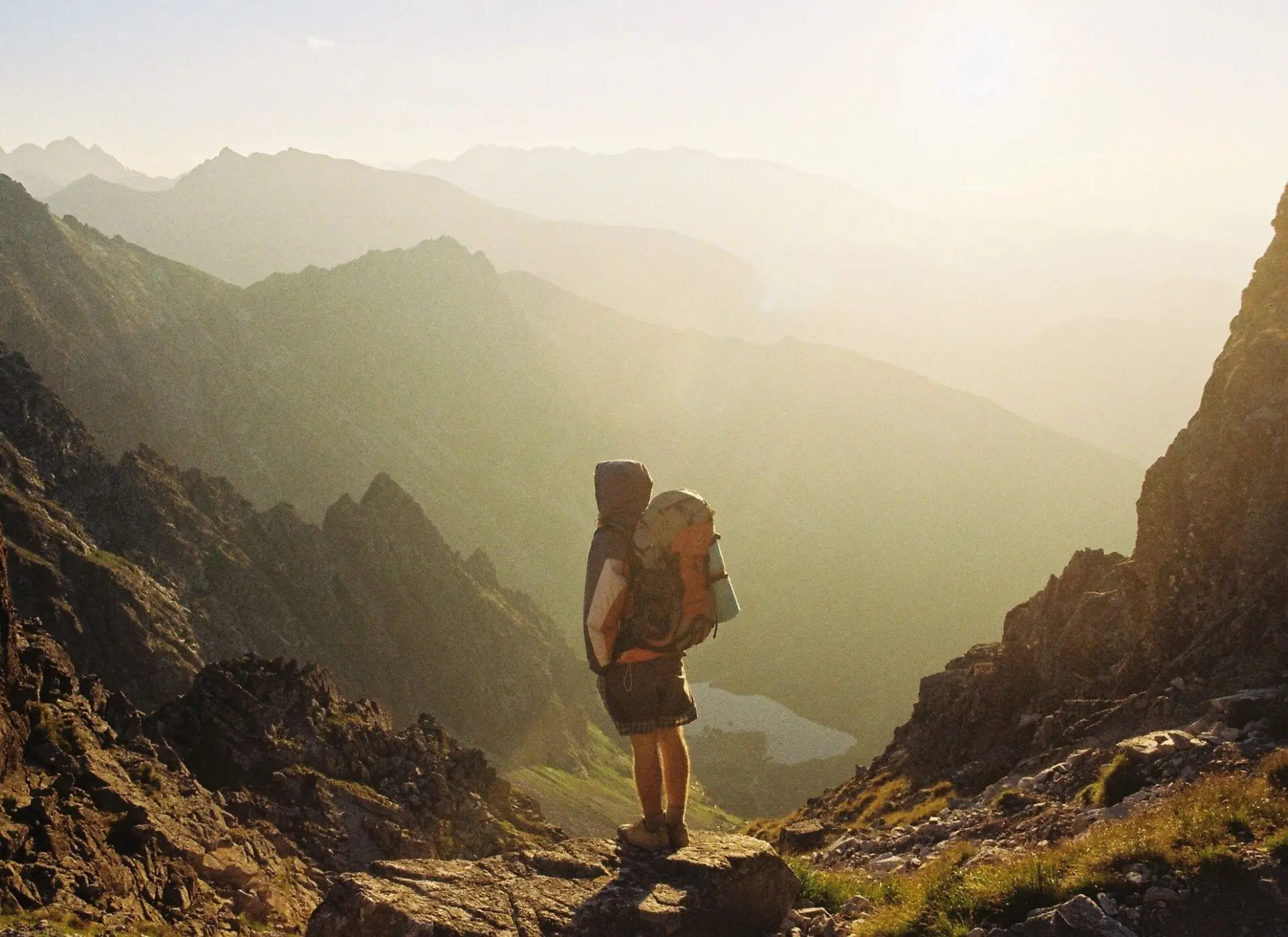 A person with a backpack is standing on top of a mountain.