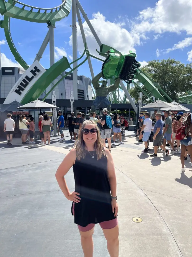 A woman standing in front of a ferris wheel.