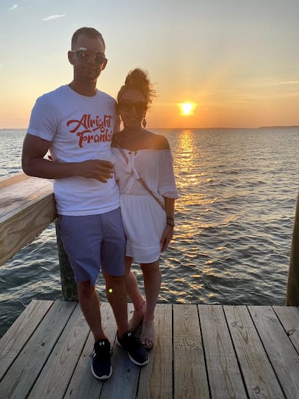 A man and woman standing on the pier at sunset.