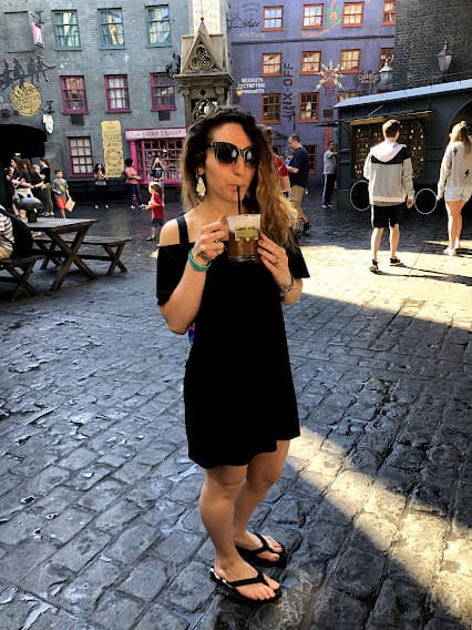 A woman in black dress holding up her cell phone.