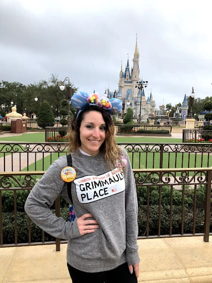 A woman standing in front of a castle with her hands on her hips.