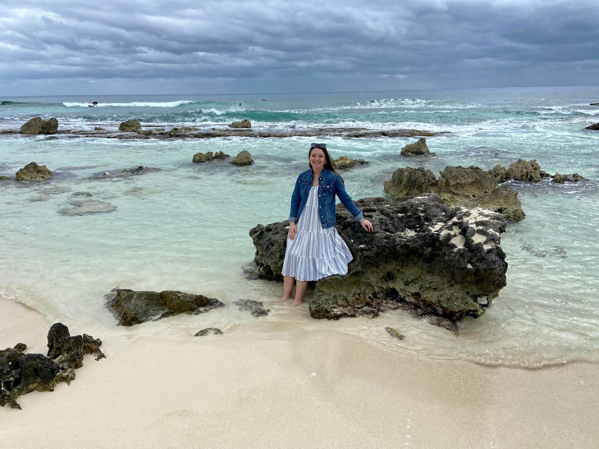 A woman standing on the beach near some rocks