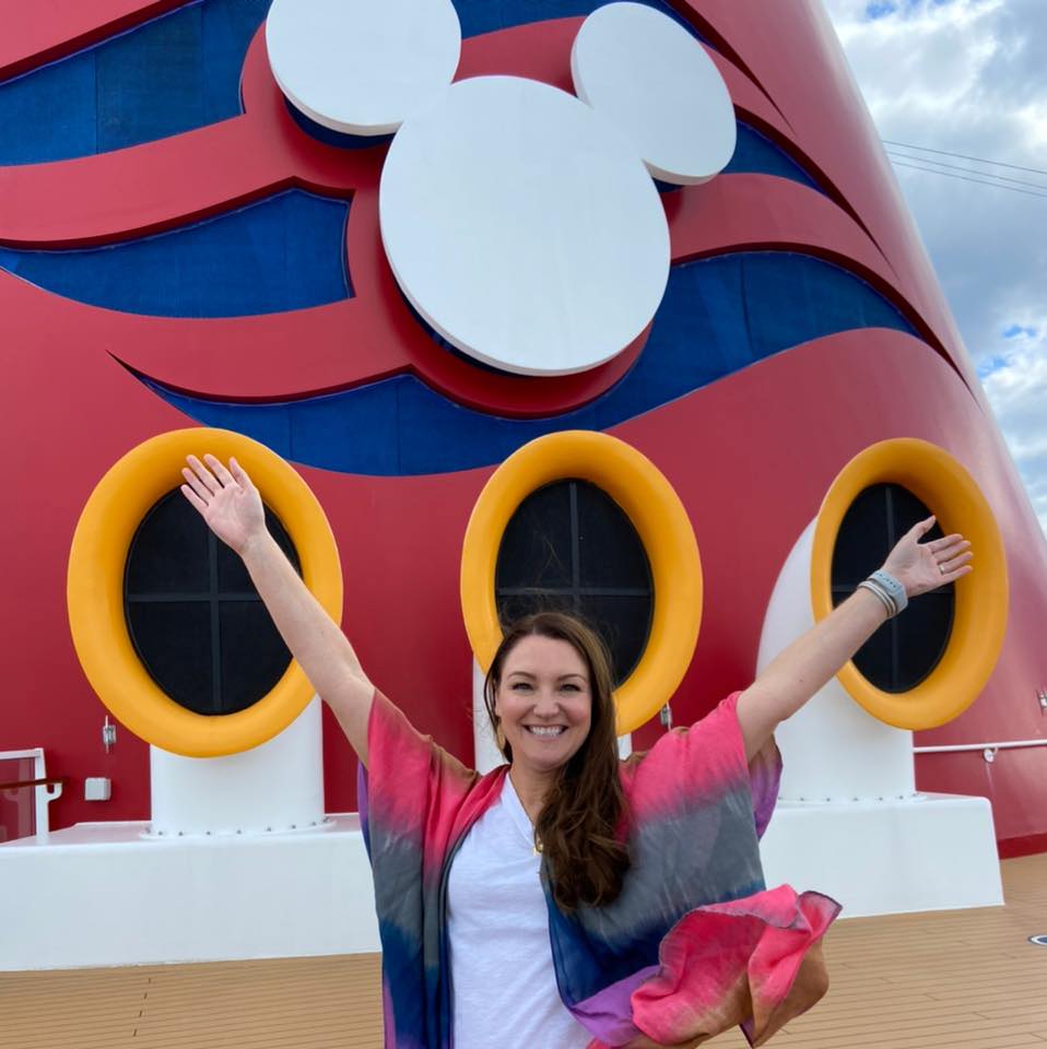 A woman standing in front of a cruise ship.