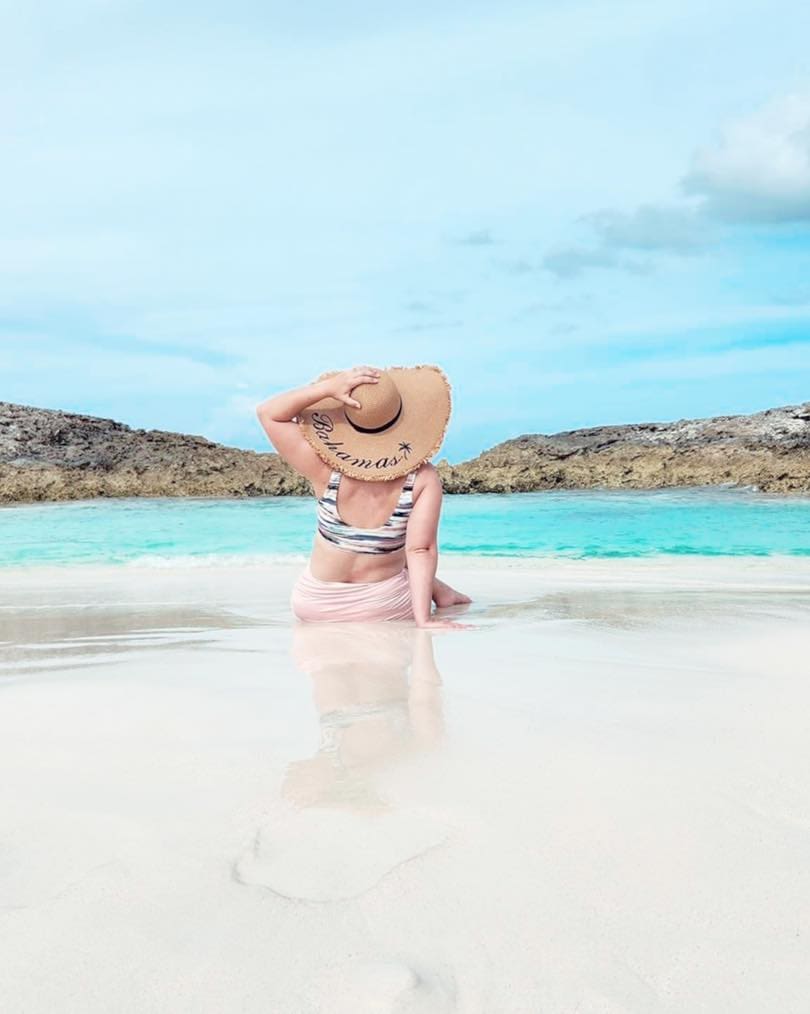 A woman sitting on the beach in the water.