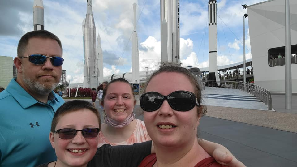 Three people standing on a bridge with the sky in the background.