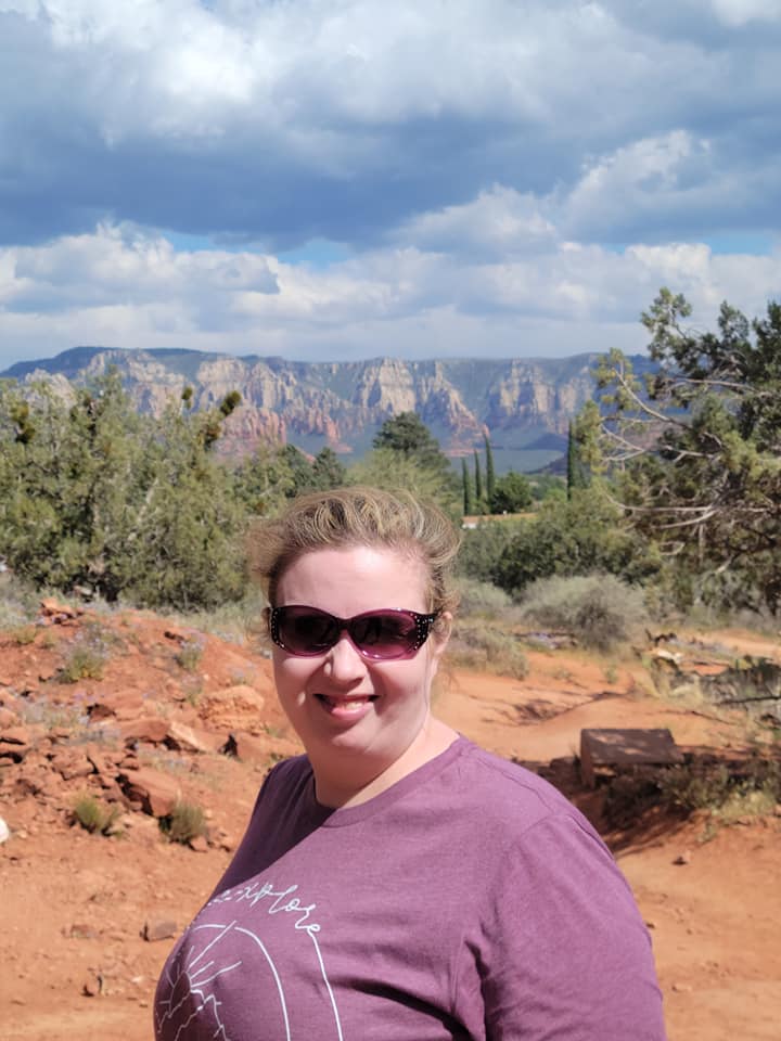 A woman standing in the desert with mountains behind her.