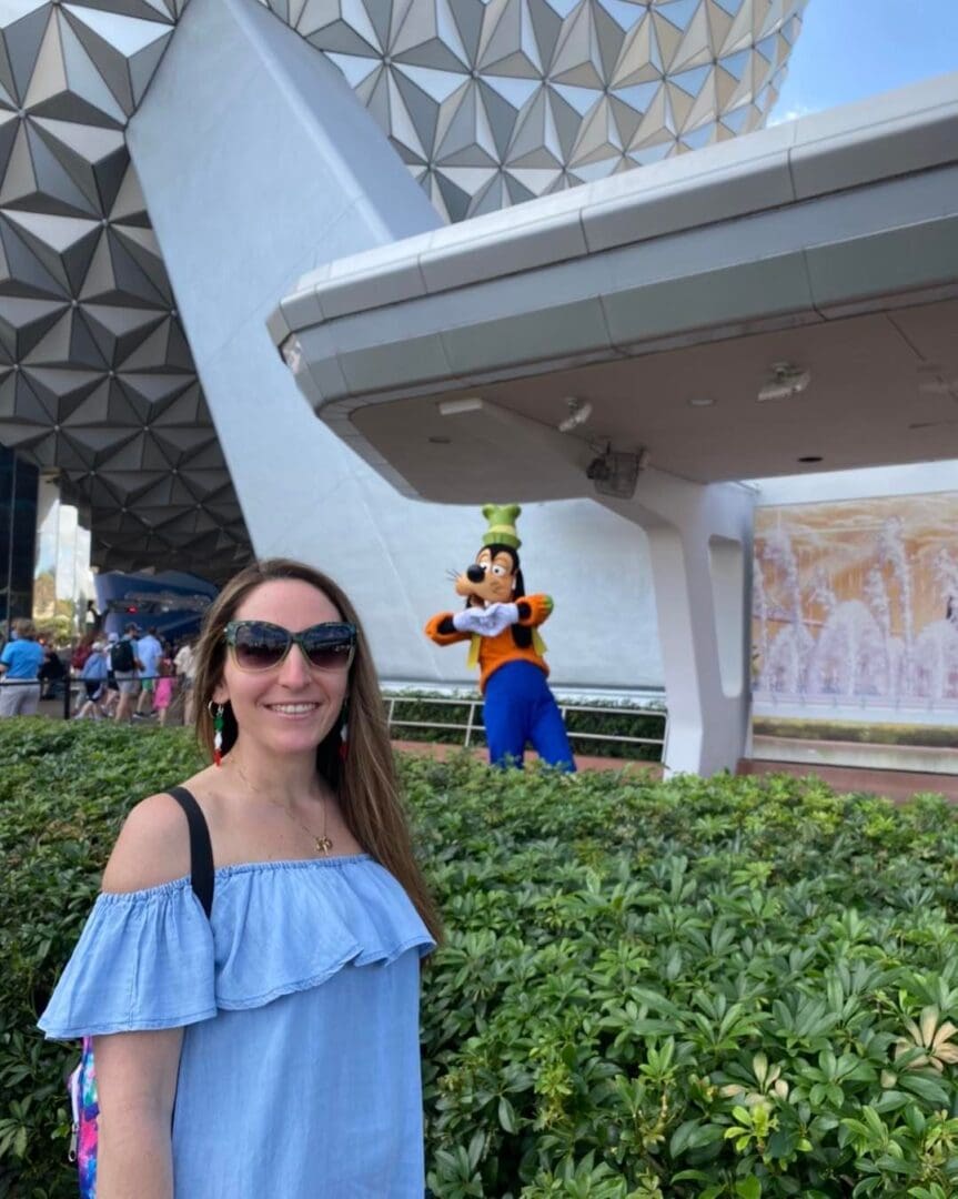 A woman standing in front of a statue of goofy.