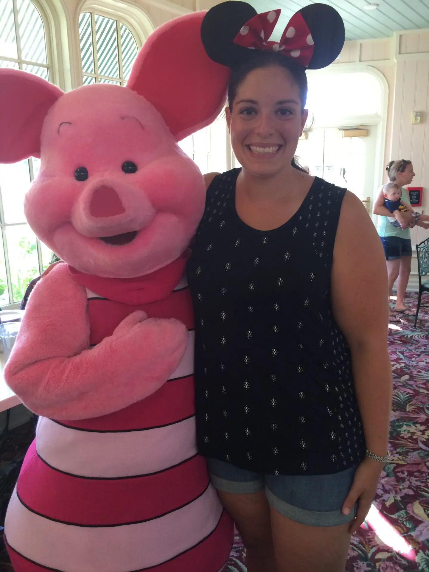 A woman standing next to a large pink pig.