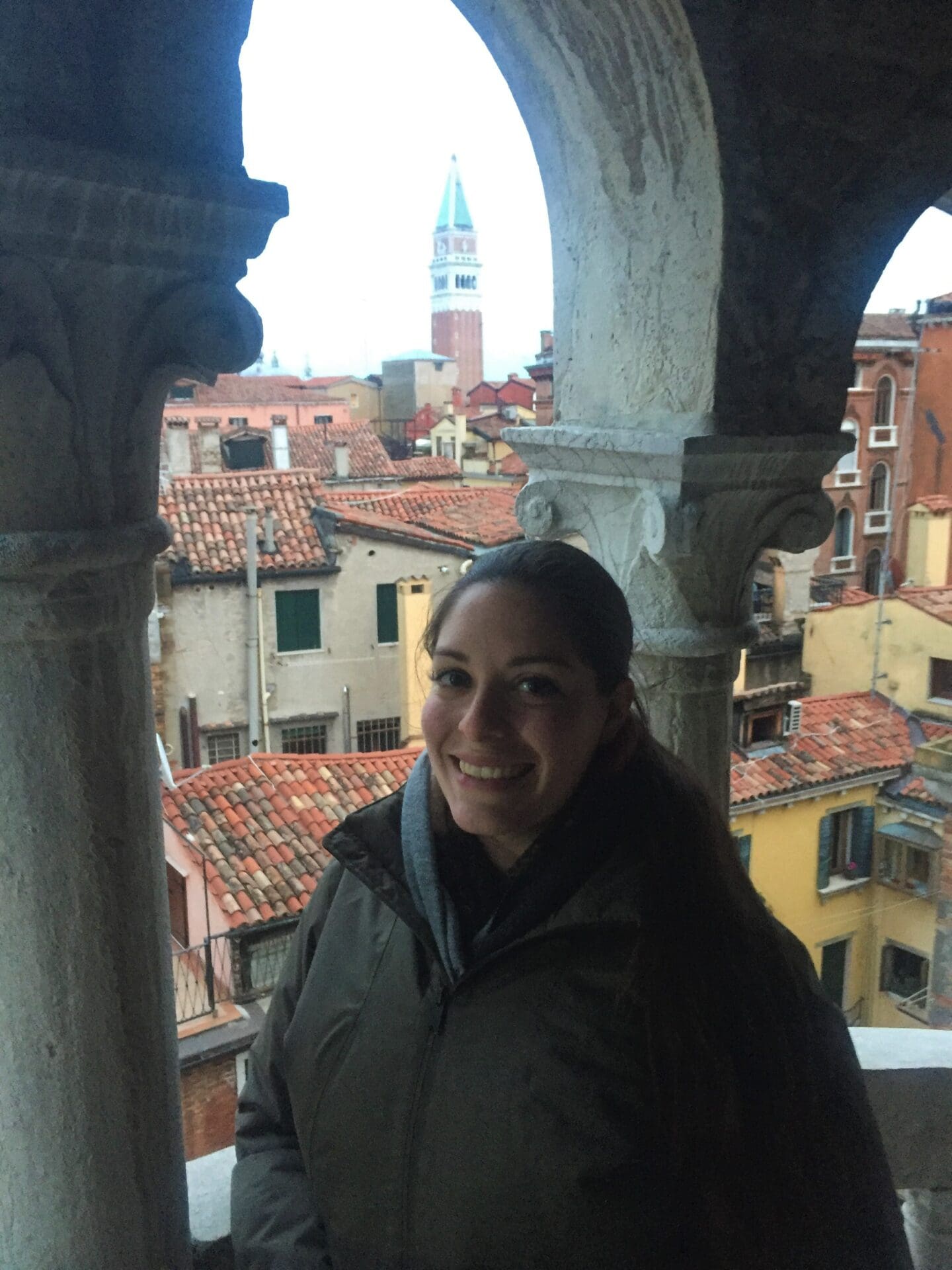 A woman standing on the balcony of an old building.