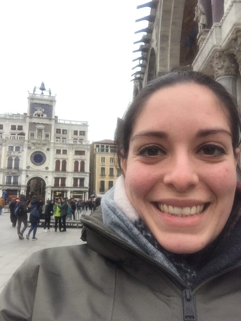 A woman smiles in front of a building.