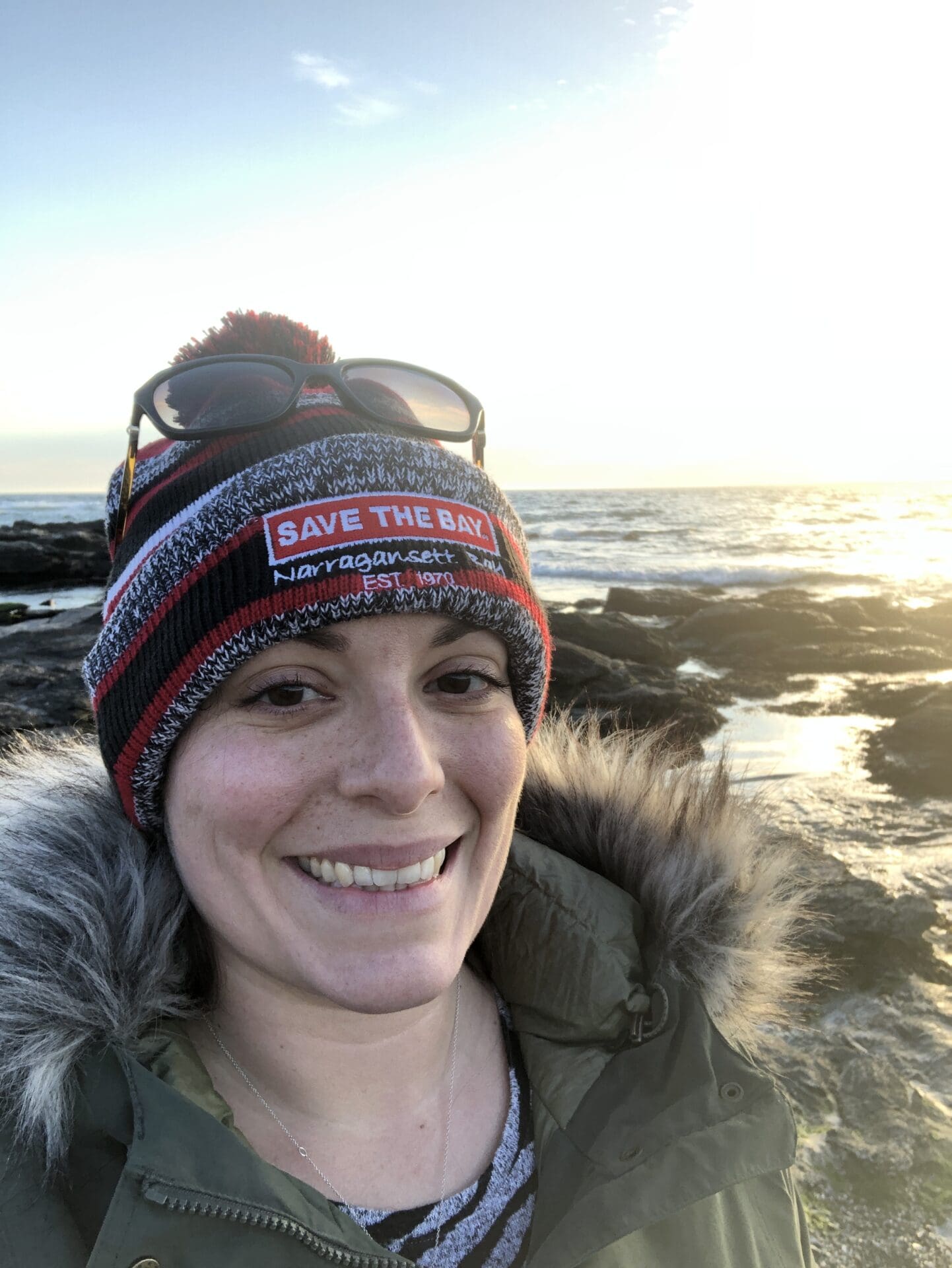 A woman wearing a hat and sunglasses on the beach.