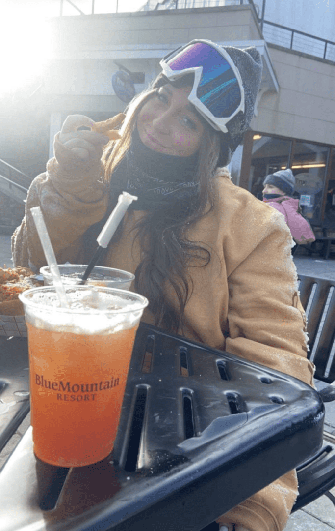 A woman sitting at an outdoor table with a drink.