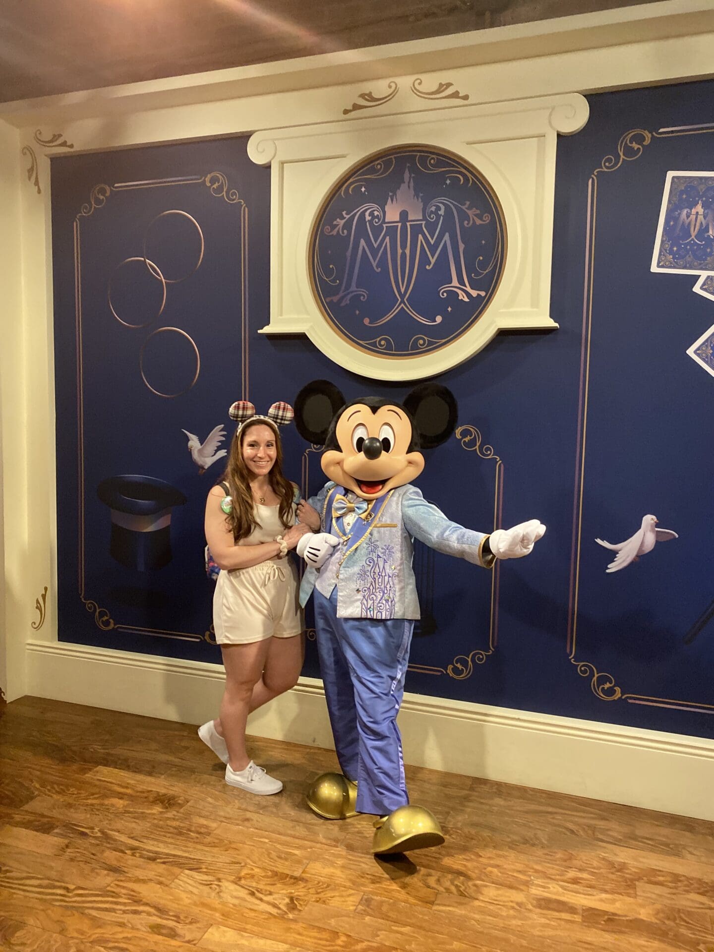 A woman posing with mickey mouse in front of a wall.