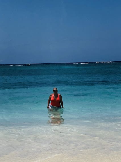 A woman in the ocean wearing an orange life vest.