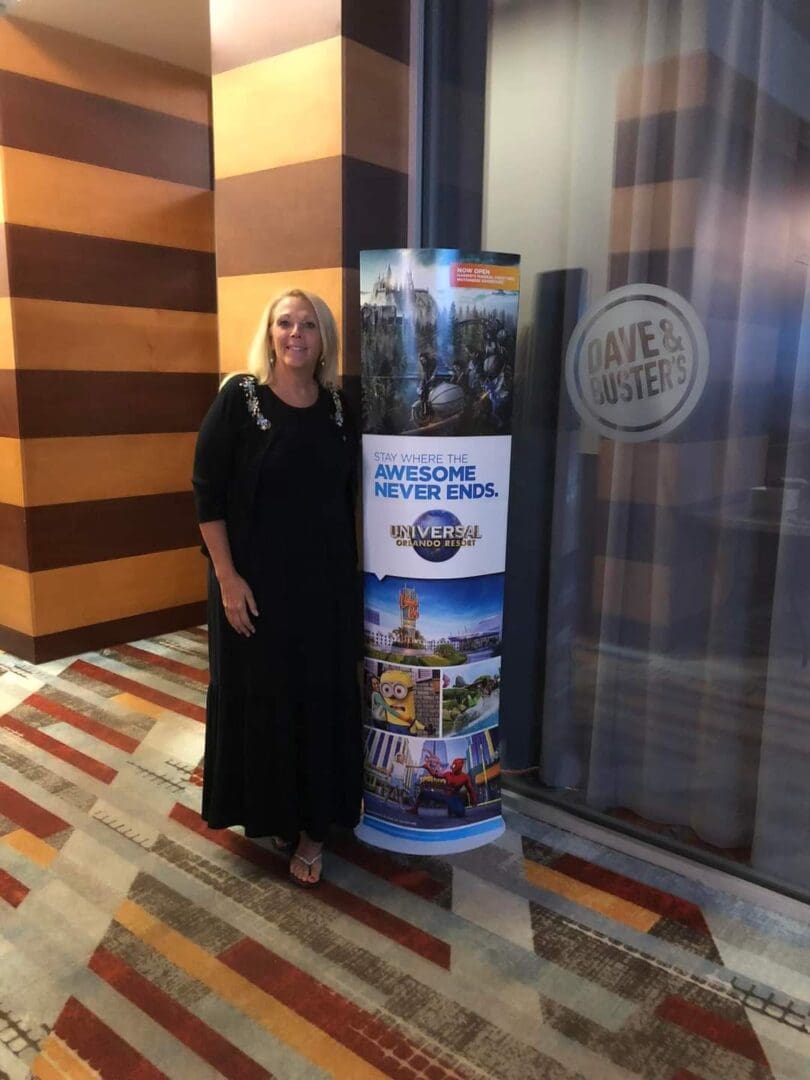 A woman standing next to a large poster.