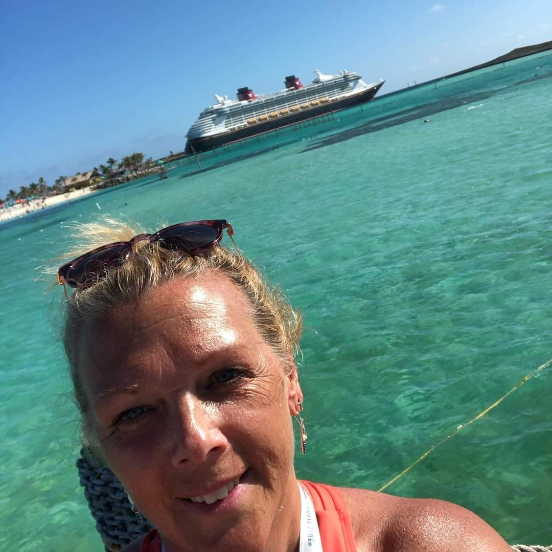 A woman in the water with a cruise ship behind her.