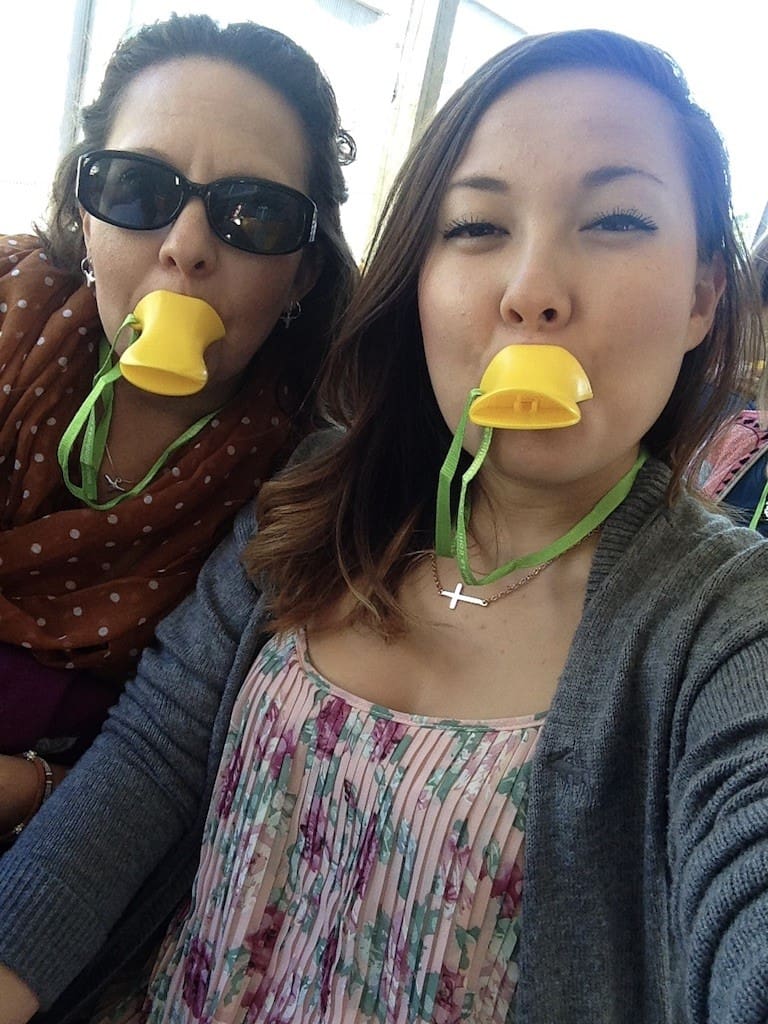 Two women with yellow cups in their mouths.