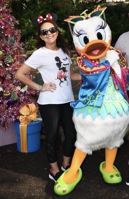 A woman standing next to a large duck statue.