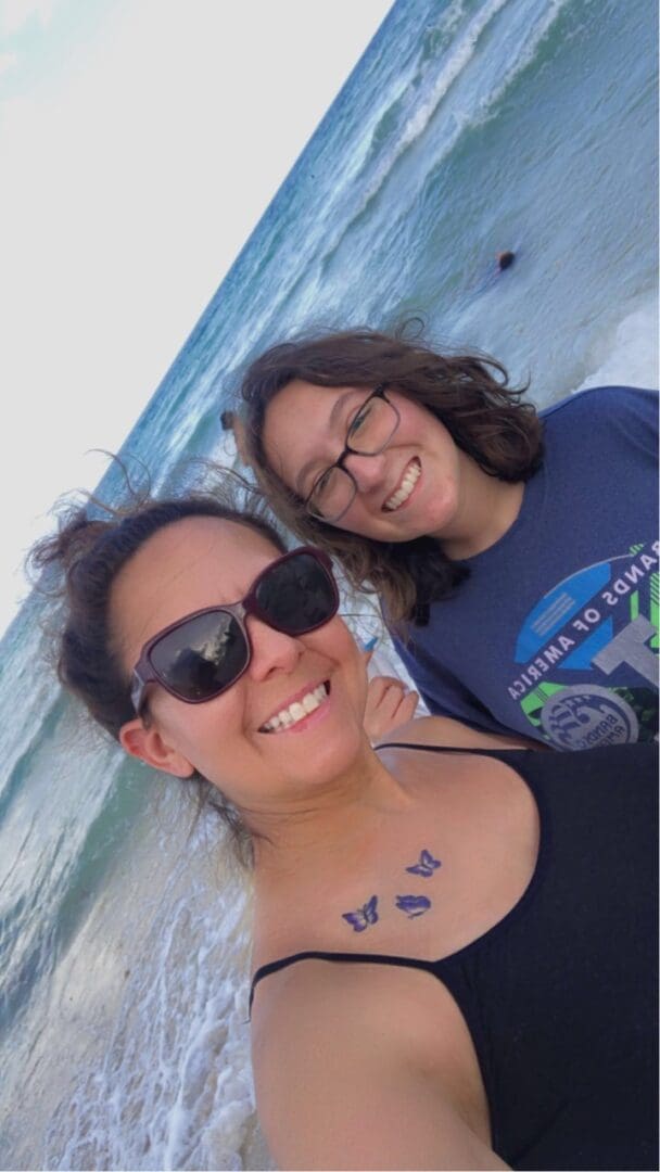 Two women standing next to each other in front of the ocean.