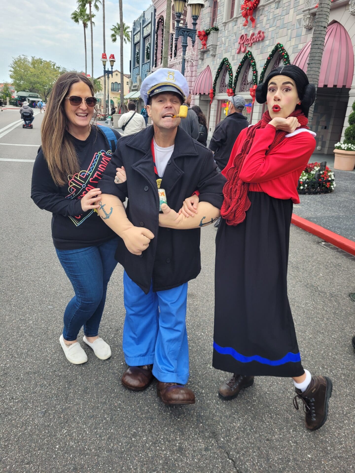 Three people posing for a picture on the street.