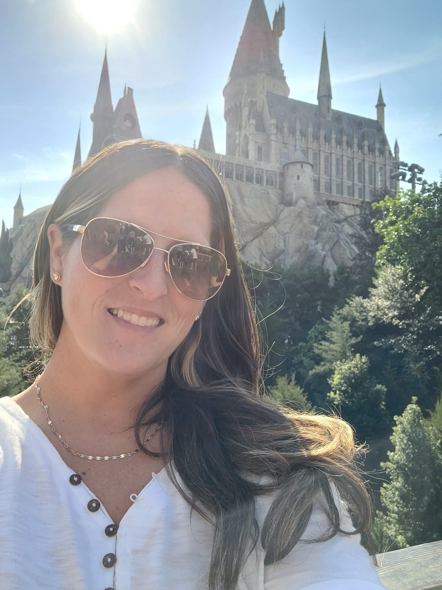 A woman in sunglasses standing outside of a castle.