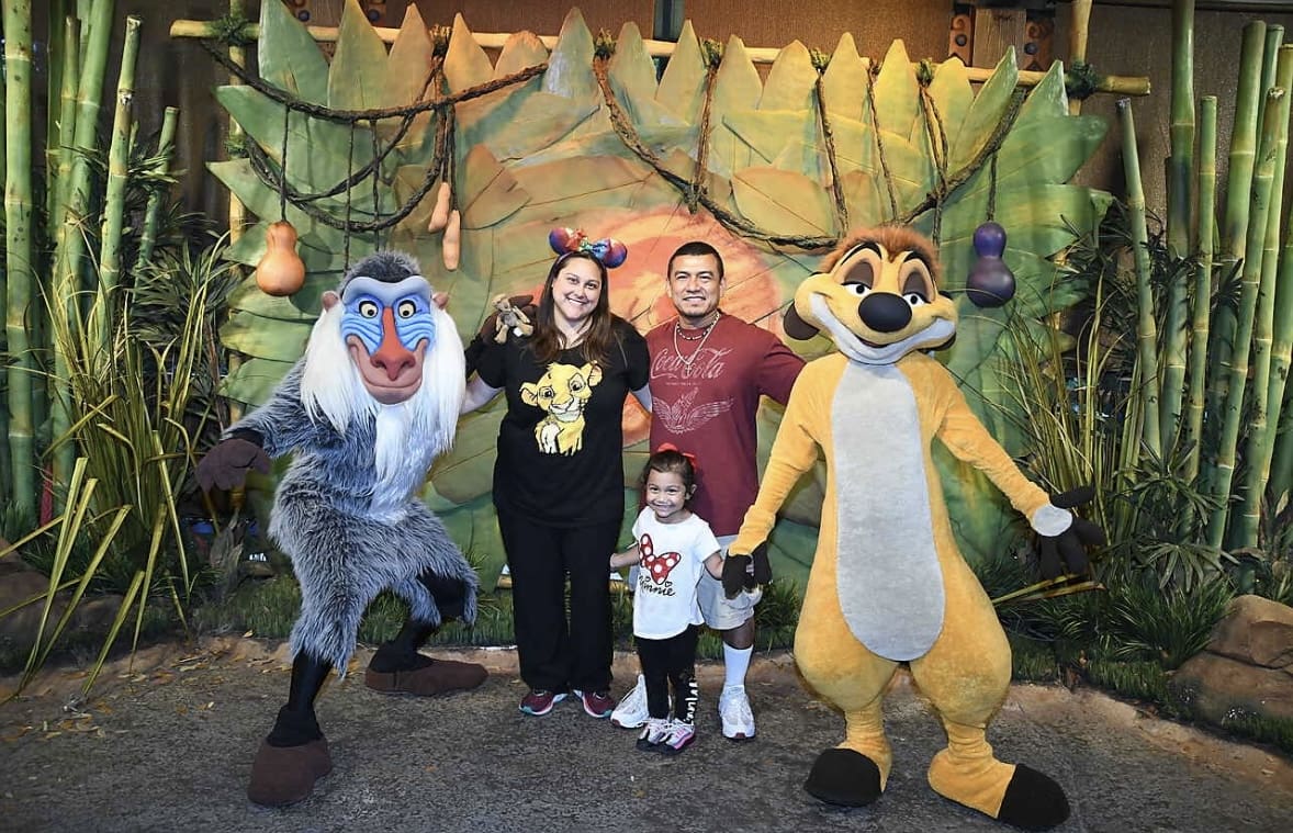 A family posing with characters from the lion king.