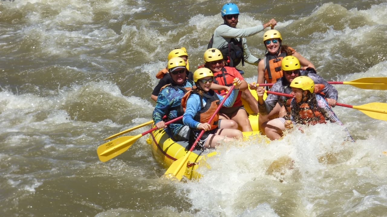 A group of people in yellow life jackets on a raft.