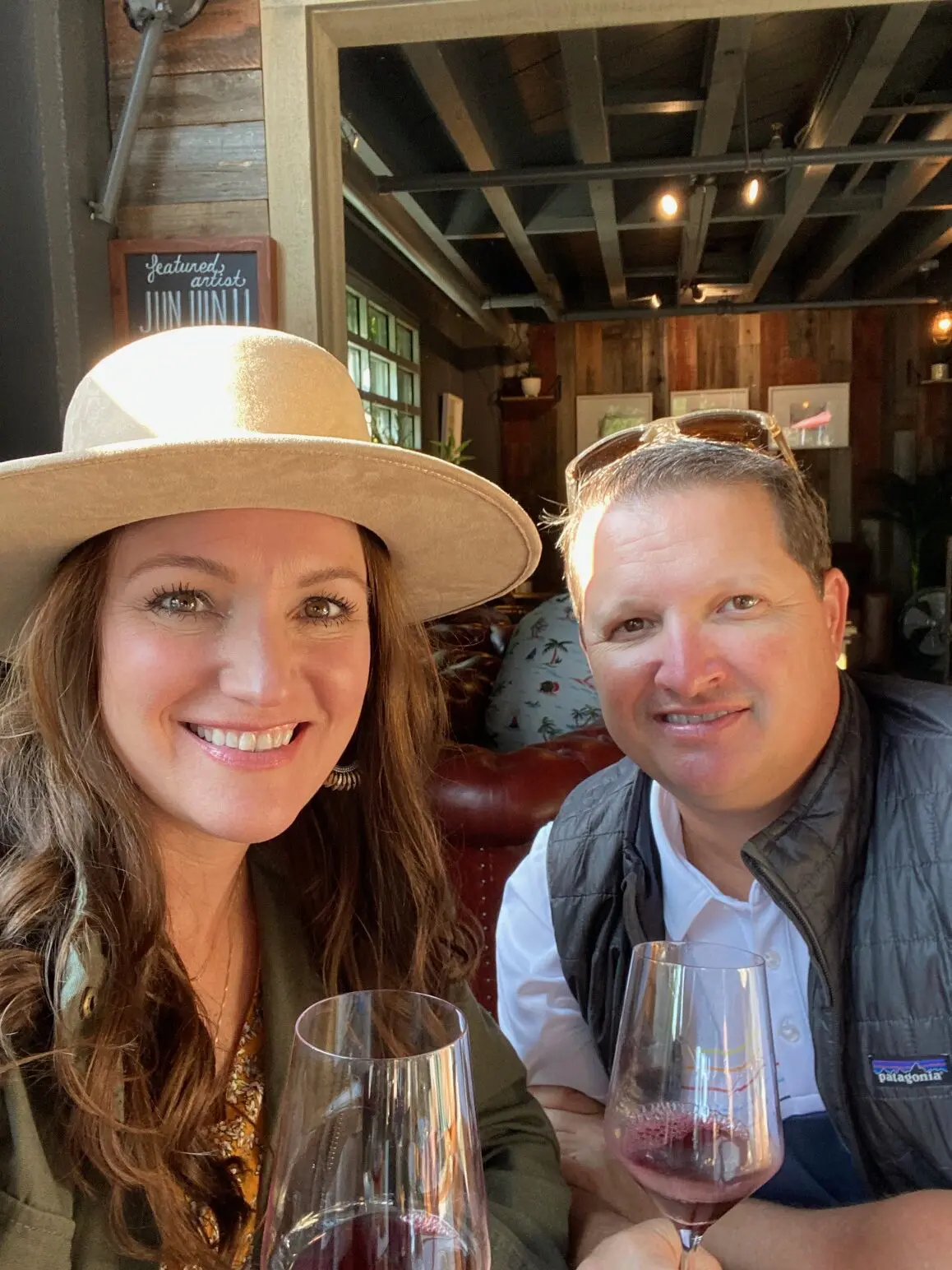 A man and woman sitting at a table with wine glasses.