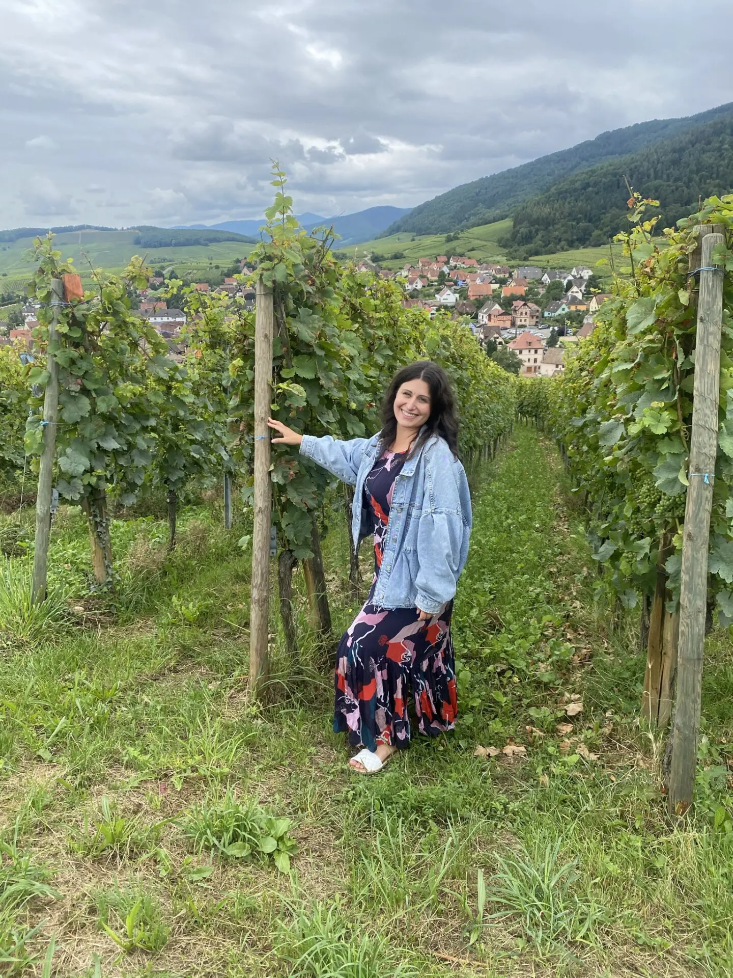 A woman standing in the middle of a vineyard.