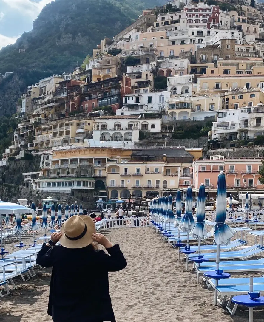 A person standing on the beach near many umbrellas