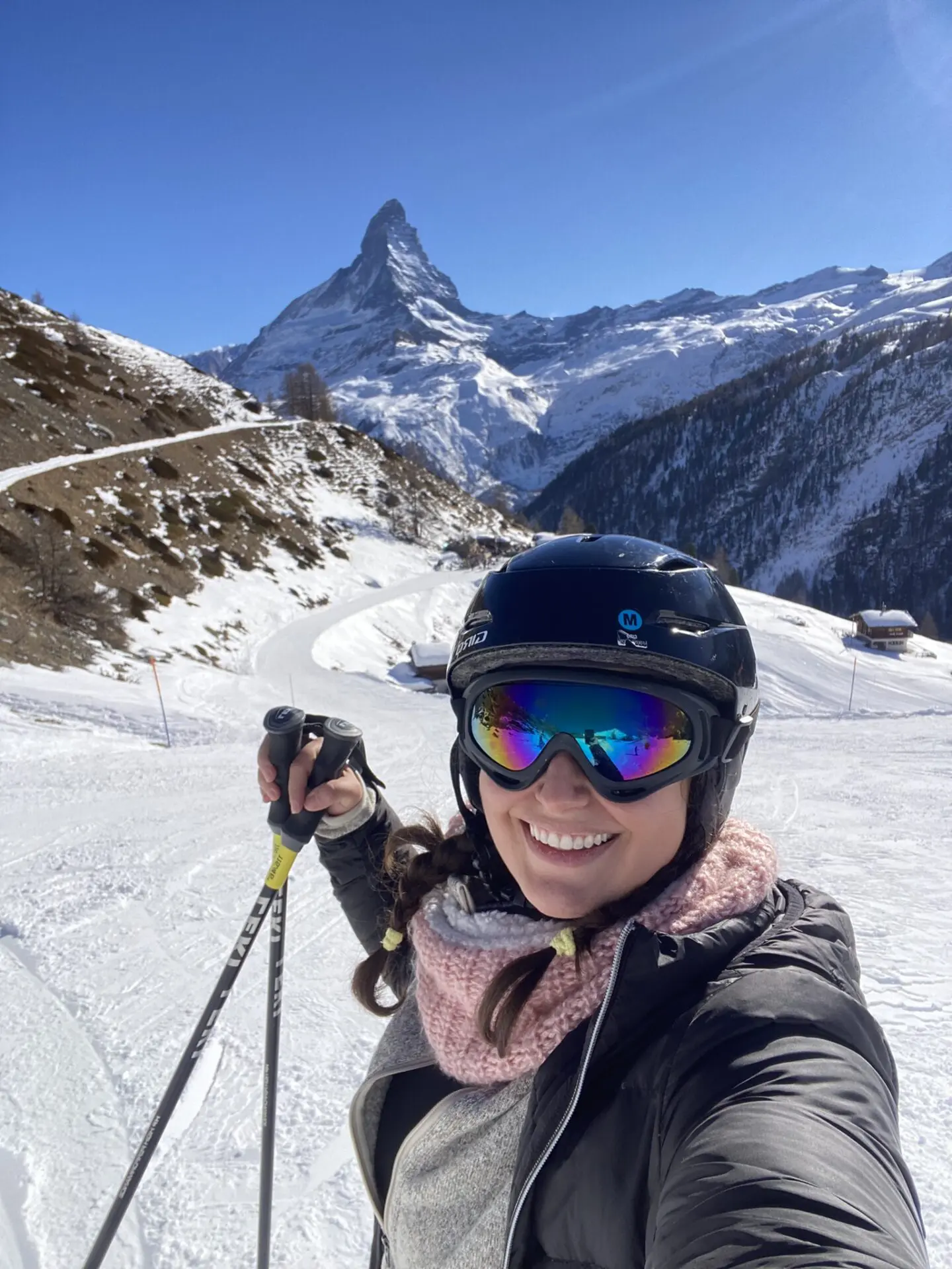 A woman in ski gear on the slopes with mountains behind her.