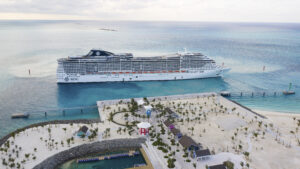 A cruise ship docked at the beach in front of some palm trees.