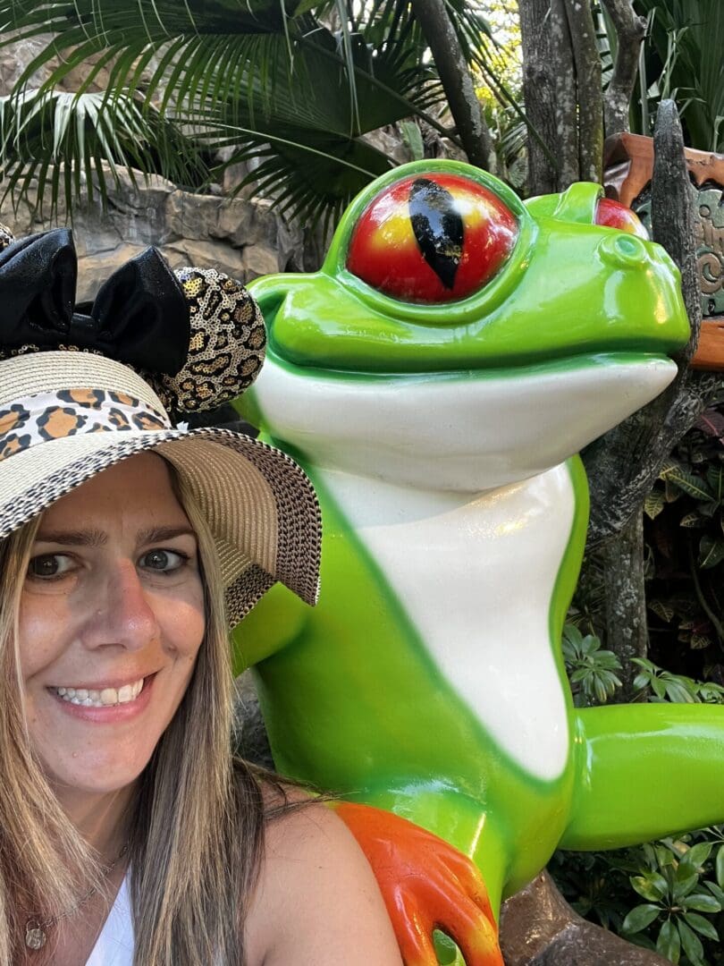 Smiling woman posing with a green frog statue.