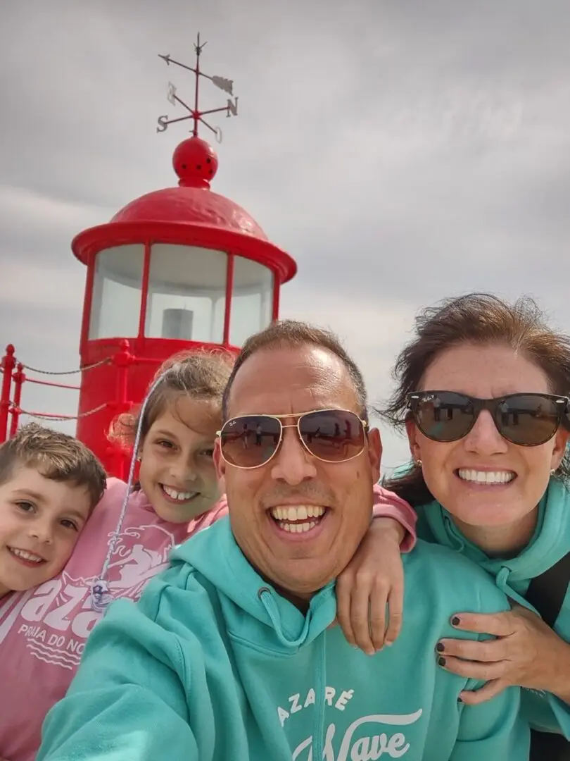 Family portrait in front of a red lighthouse.