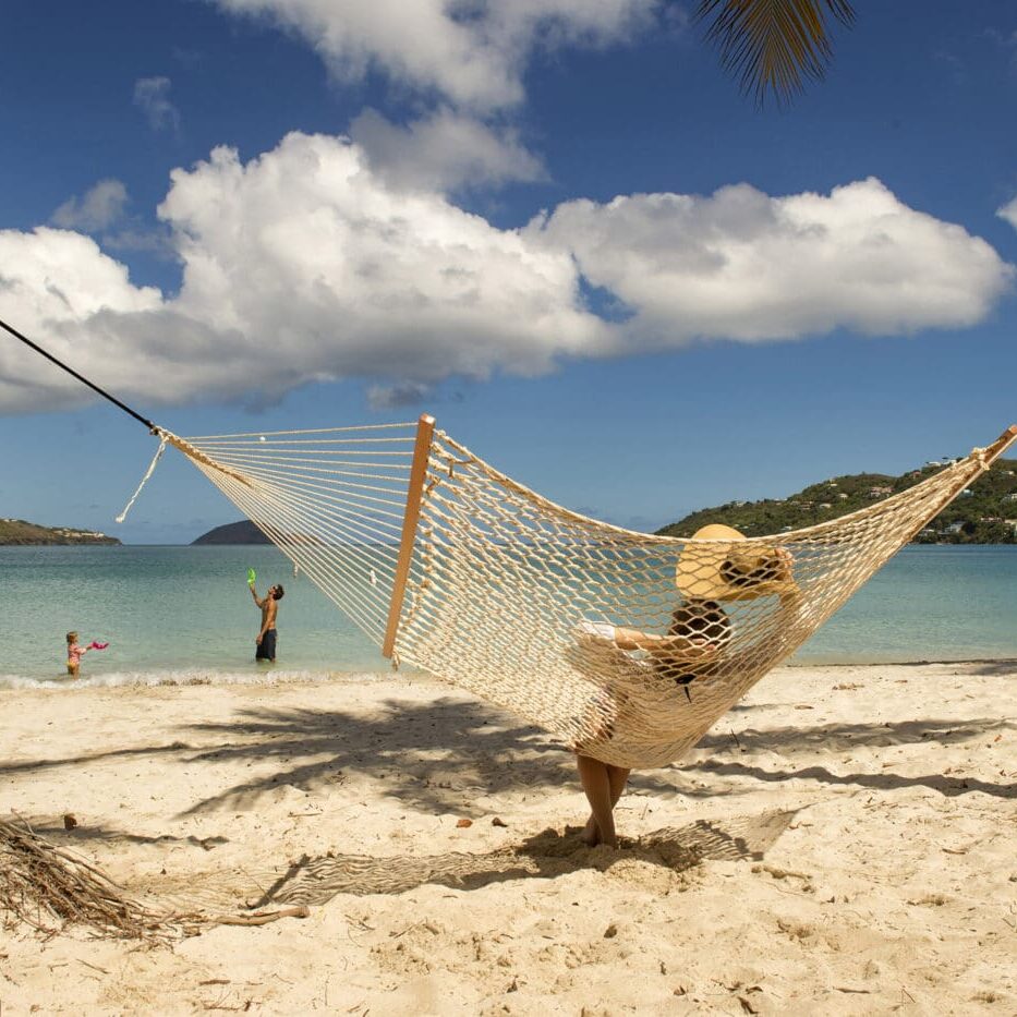 A person is laying in a hammock on the beach