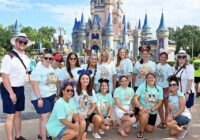 A group of people posing for a picture in front of a castle at walt disney world
