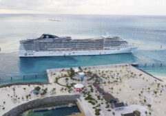 A cruise ship docked at the beach in front of some palm trees.