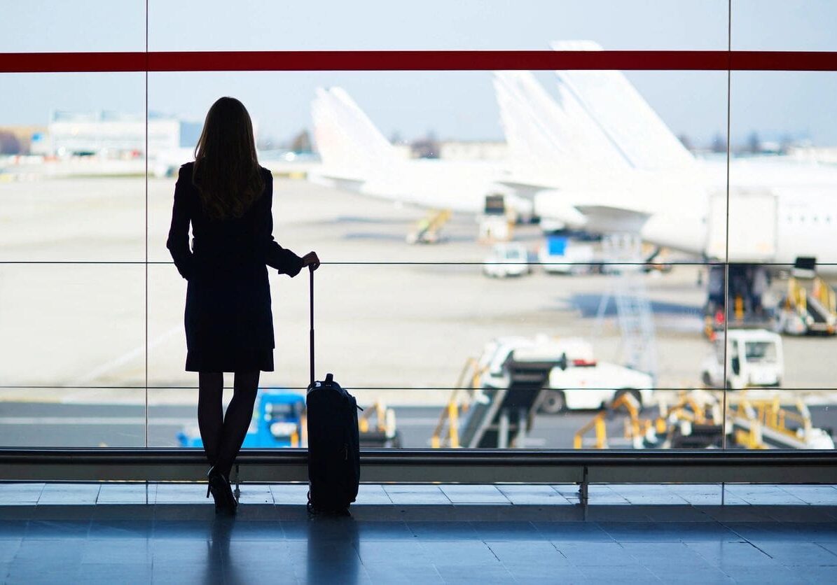 A woman standing in front of an airport window.